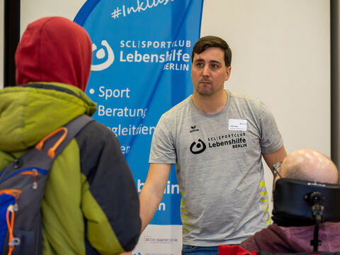 Ein Mitarbeiter des SCL Sportclubs Lebenshilfe Berlin informiert über inklusive Sportangebote.